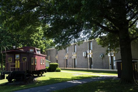 Picture of the outside of Brunswick High School building, with trees and a garnet model train car from The Frederick News Post