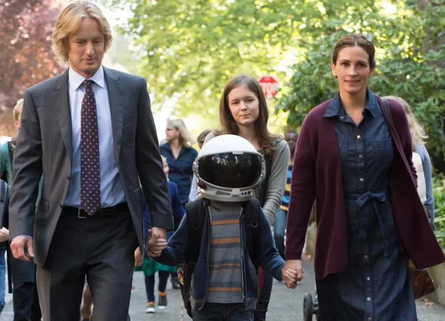 Owen Wilson who plays Nate Pullman and Julia Roberts who plays Isabel Pullman holding Auggies hands while hes wearing his astronaut helmet. 