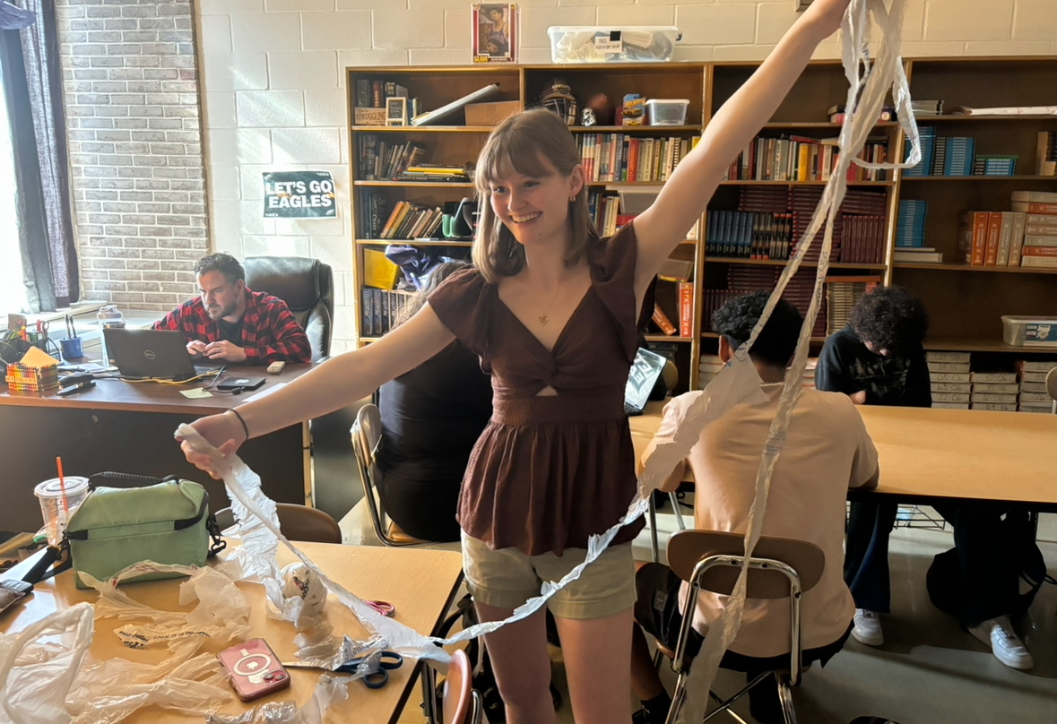 Paige Trendell holds up a long, plastic bag strip that will be made into a yarn-ball, then crocheted into a mat.