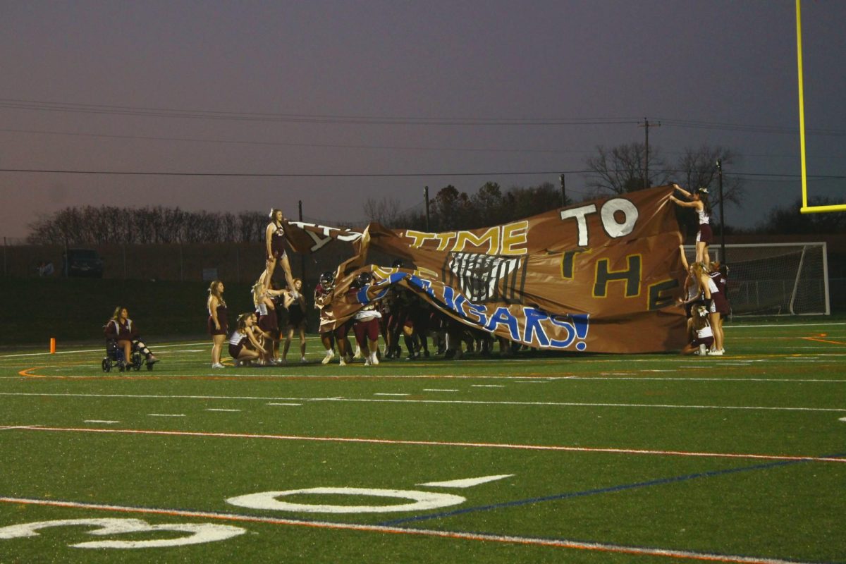 The team runs through the banner.