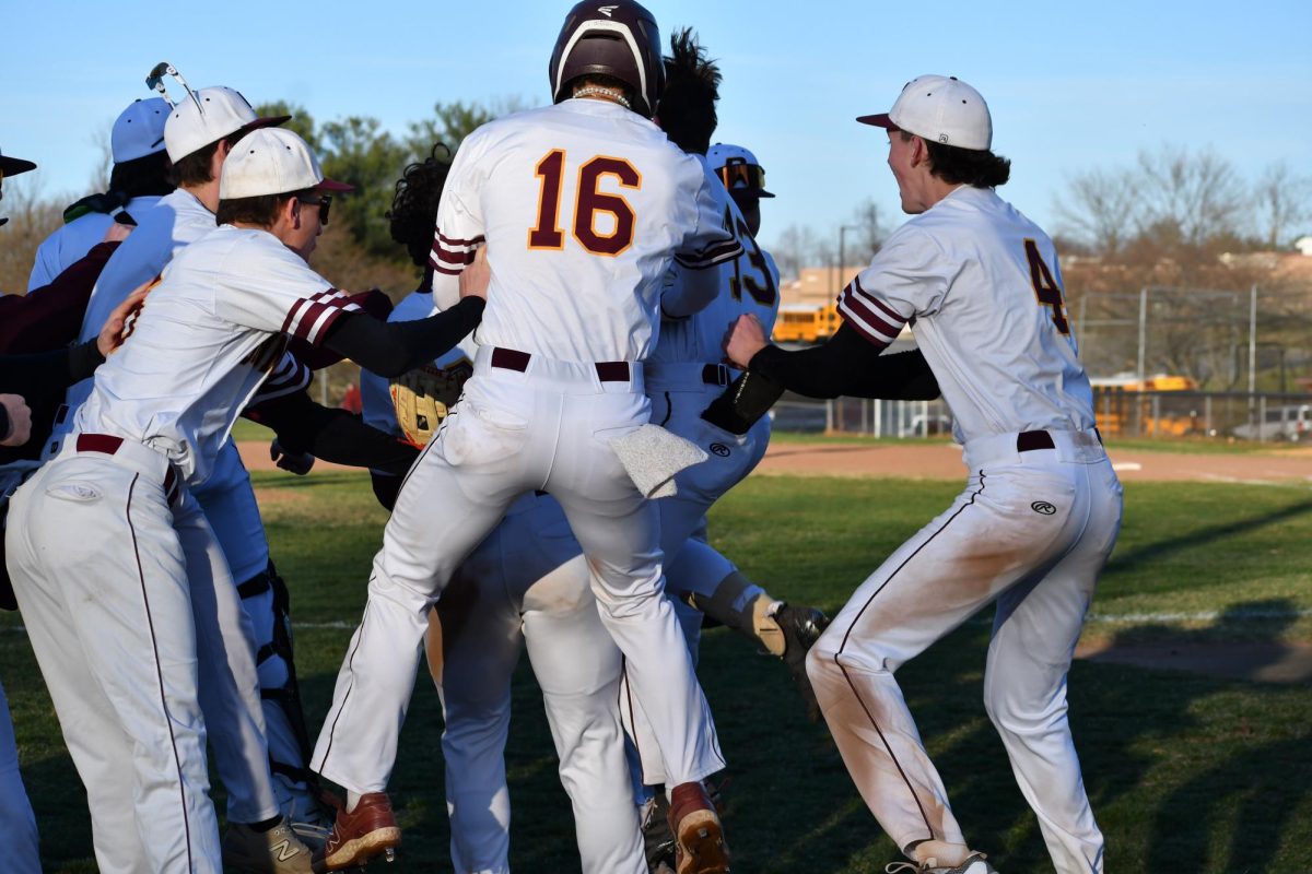 Sam Verosto, senior #16, Colin Pearre, senior #4, and others jumping up and down after a run scores. 