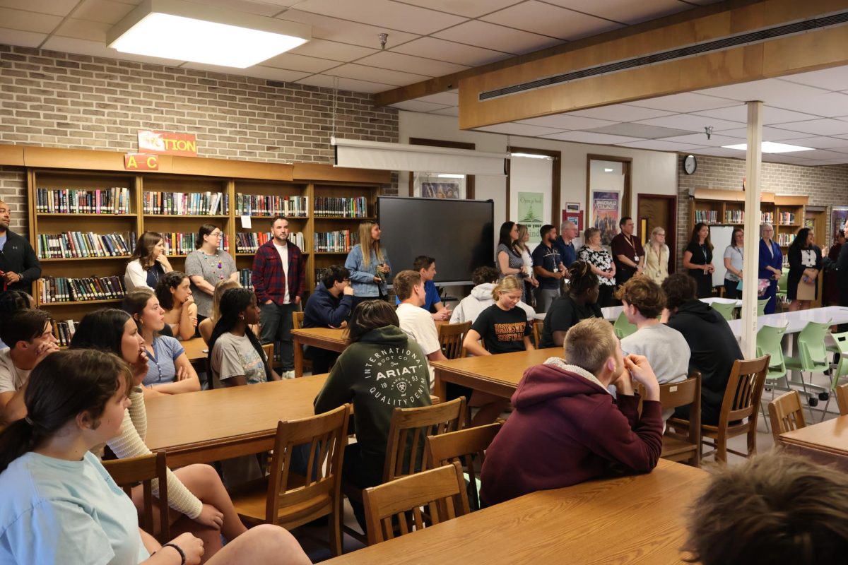 The library is full with observers and their attention is directed towards Mrs. Kowalski!