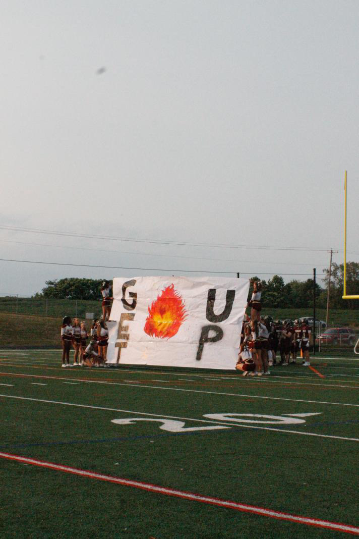 Brunswick's Varsity Cheerleaders hold up a "Get Fired Up" banner before the football players enter onto the field.