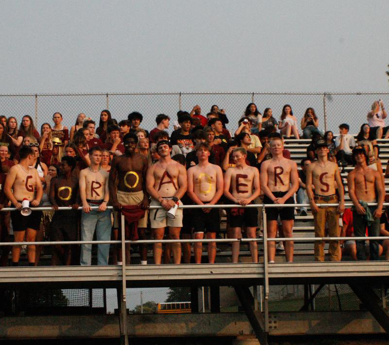 10 boys from the student section paint "Go Roaders!" on their chests.