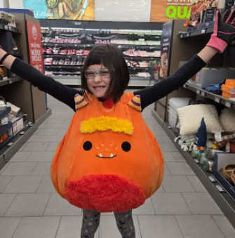 Millie Holdridge trying on silly costumes in the middle of a store.