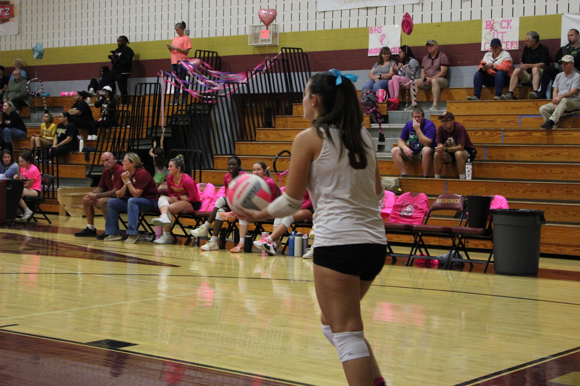 BHS Varsity Volleyball Caption, Isabella Brisbane serving a ball, during "Dig Pink" night.