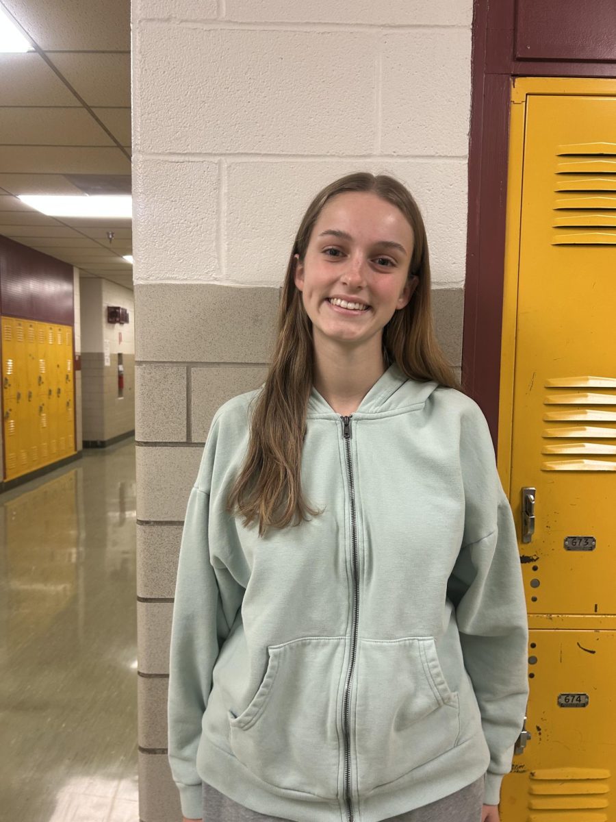 Caroline Teague's smiles in the english hallway for a picture.