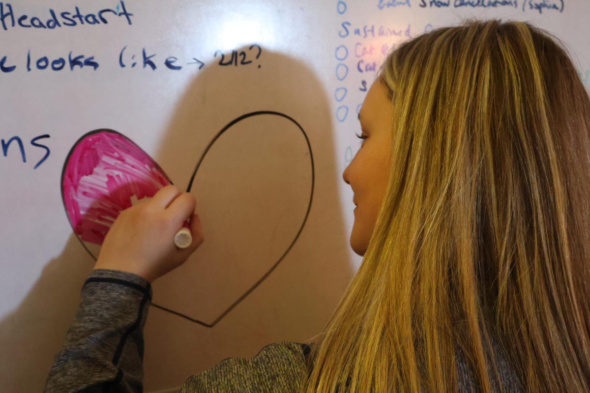 Student Julia Thompson coloring in a heart around Valentine's Day.