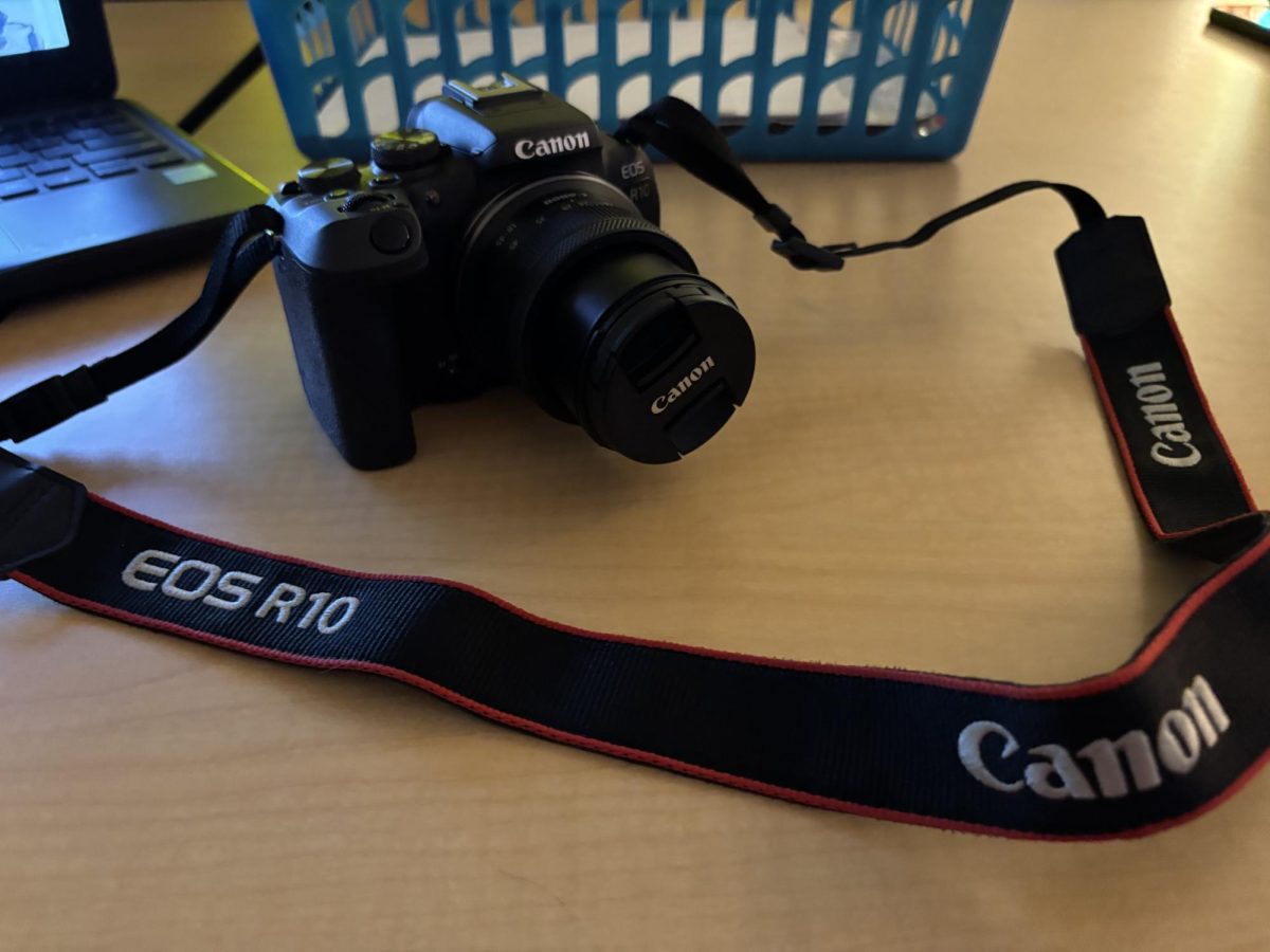 An R10 EOS Canon Camera is shown laid out on a table during journalism class.
