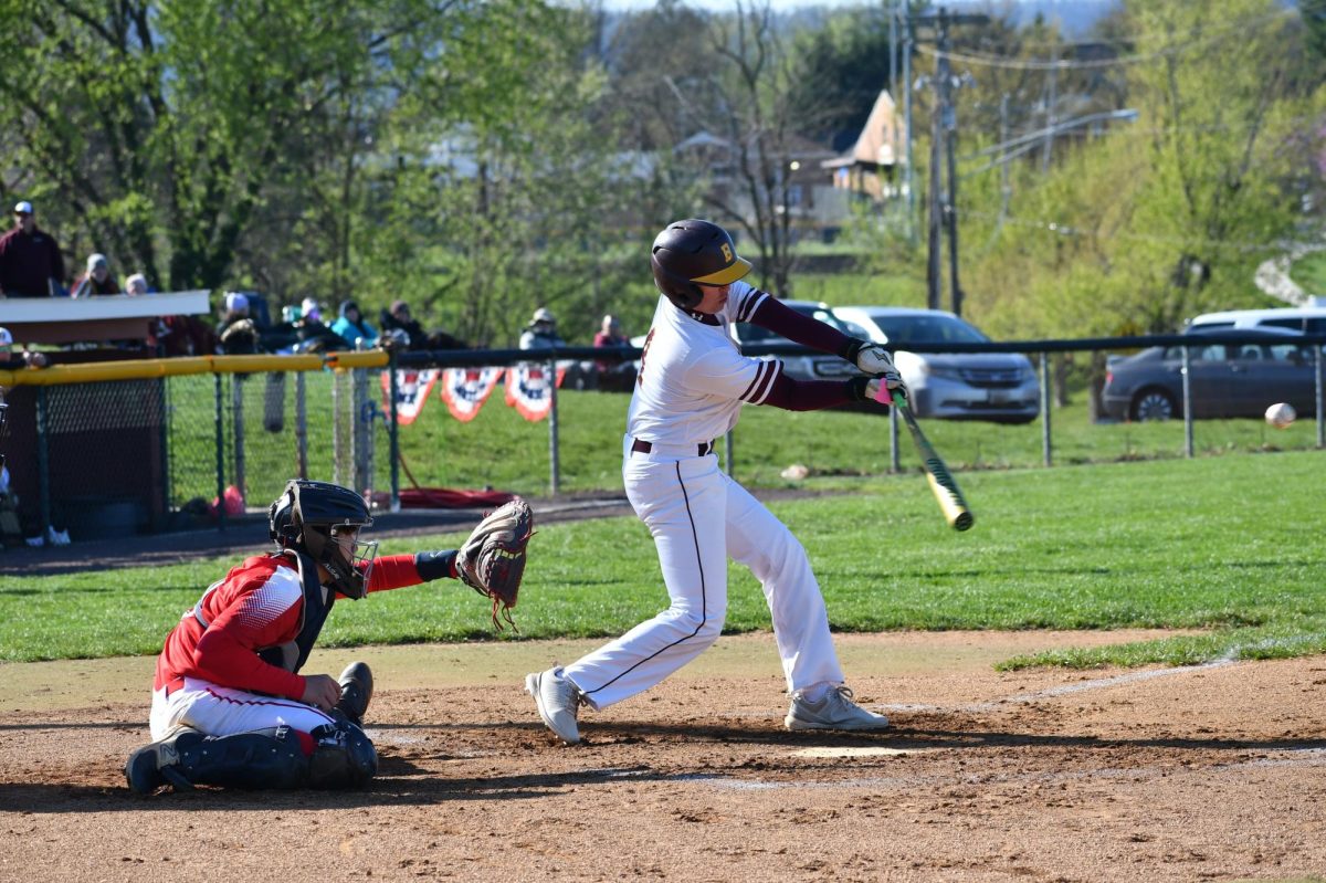 Pitcher, Zach Via, senior, swinging and getting a base hit. 