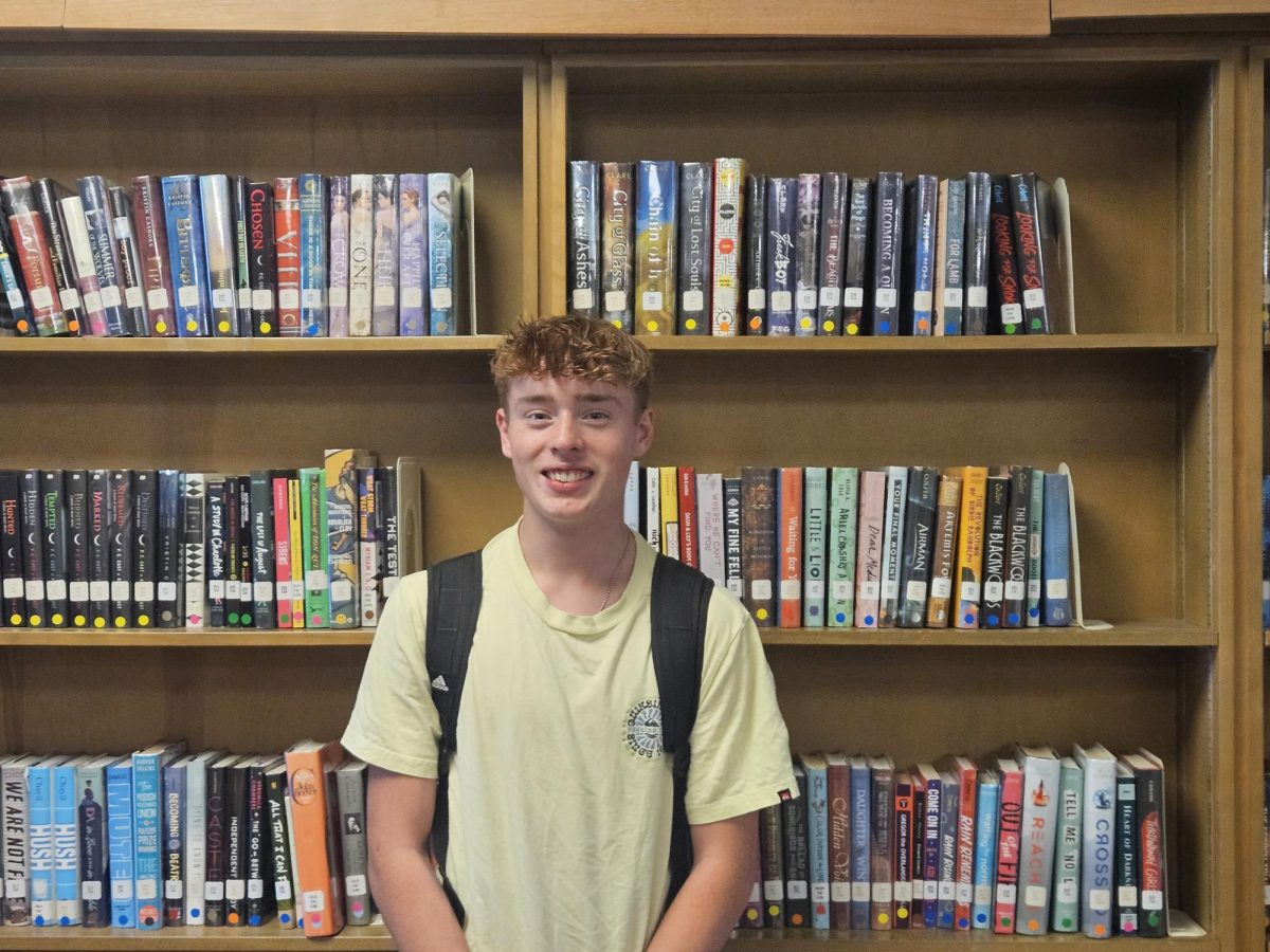 Photo of Rowan Williams in the BHS library standing in front of the bookshelves.